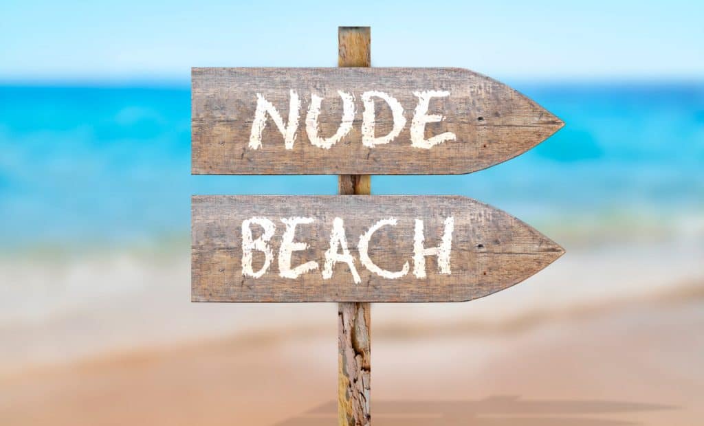 sign pointing to a nude beach